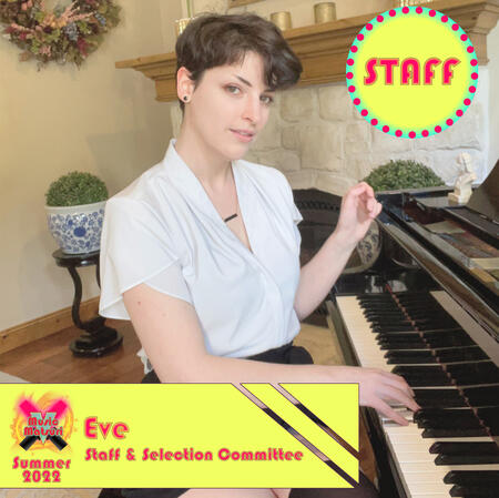 Eve, a white person with very short brown hair and wearing a white top. Sitting at a piano.